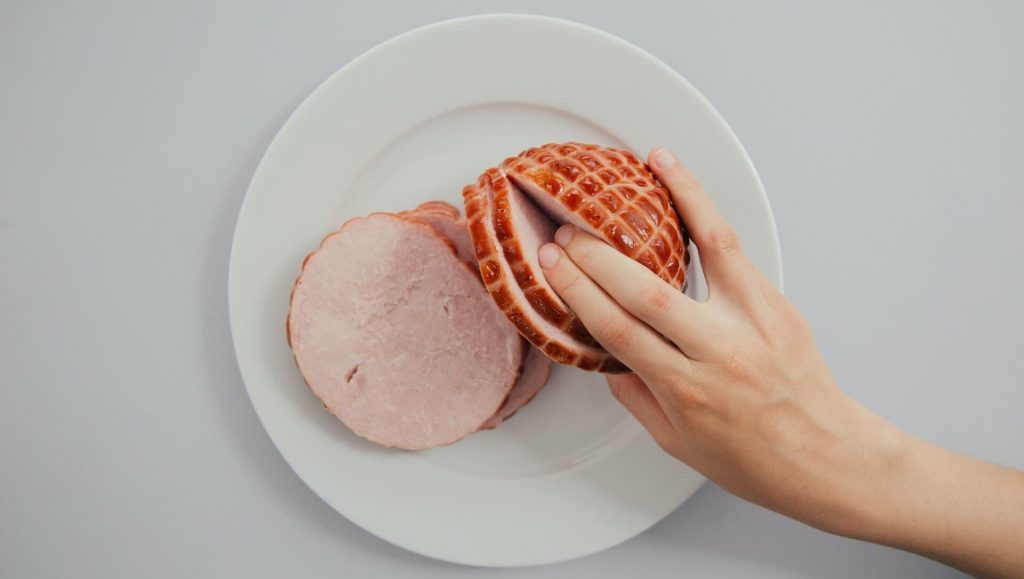 A person putting two fingers inside a ham